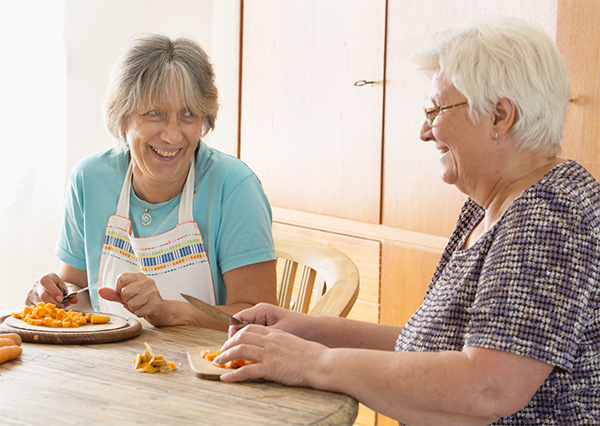 Deux femmes âgées souriantes qui préparent des légumes pour le repas