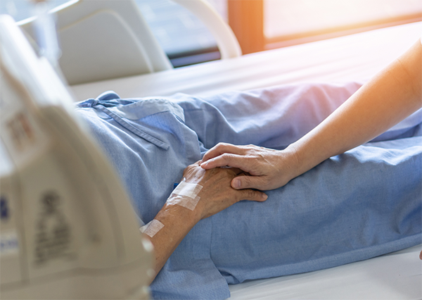 Soignant tenant la main d'une personne mourante dans un établissement de soins palliatifs